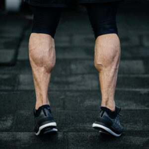 trained legs with muscular calves in sneakers in training gym
